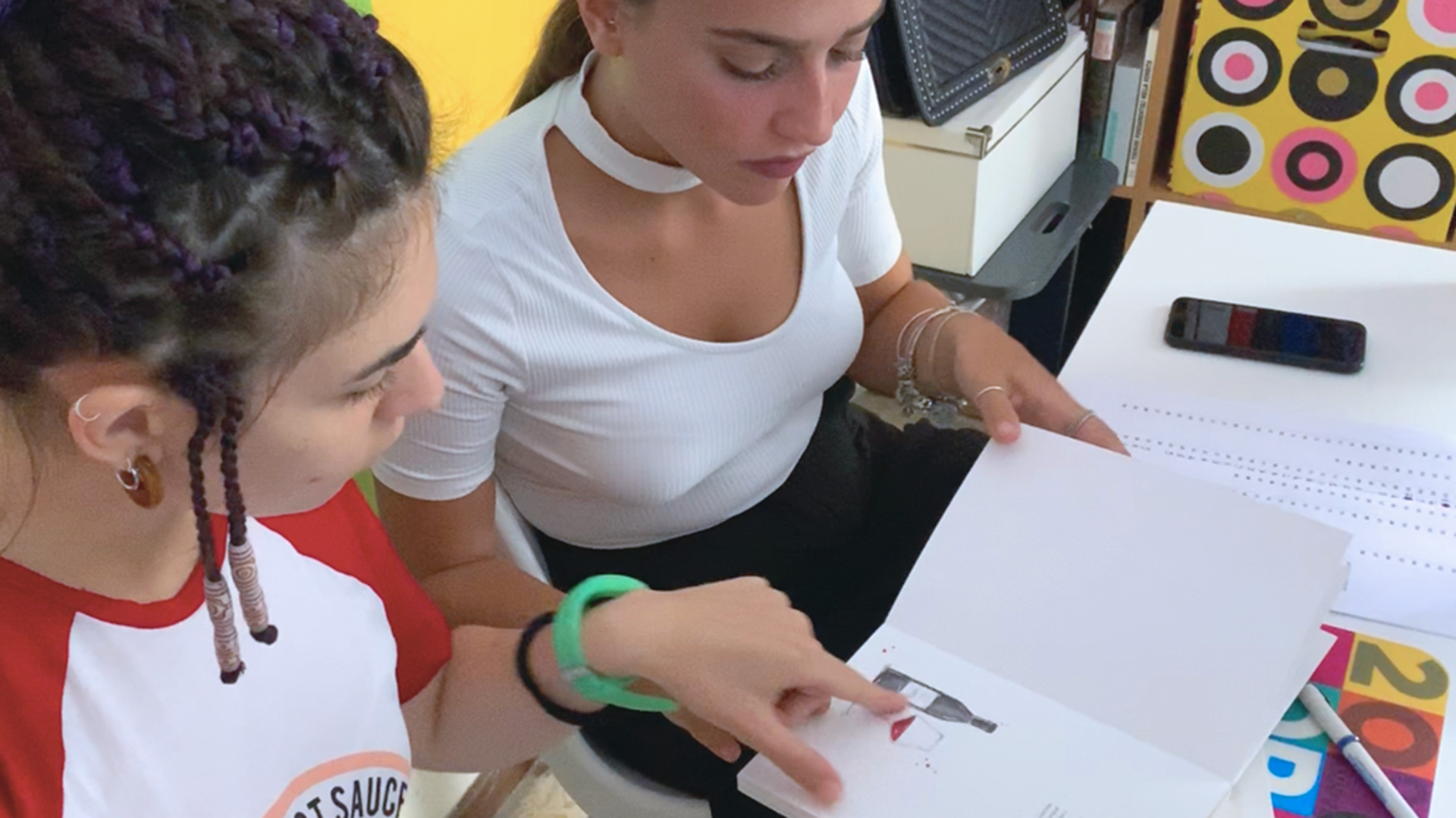 Tavolo di lavoro con manifesti stampati, cataloghi e inserti di un festival del cinema, accanto a un iMac che mostra la grafica